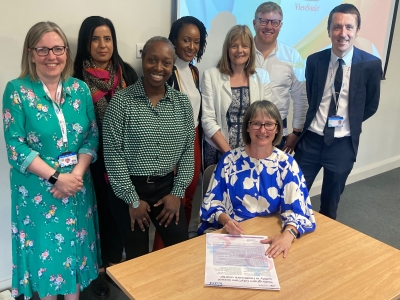 Lou Bainbridge signs the charter, flanked by colleagues.jpeg